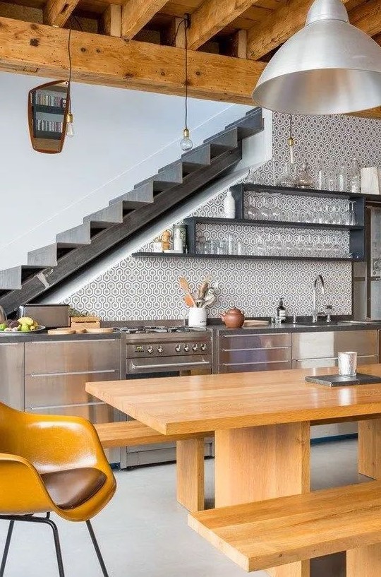 a stylish, modern kitchen in the stairwell with metal cupboards, open shelves, a wooden dining set and hanging lamps