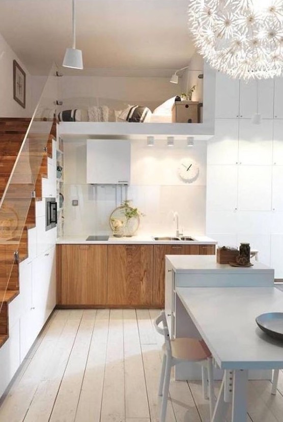a stylish Nordic kitchen with stained base cabinets, a staircase that offers plenty of storage space and a white kitchen island with table