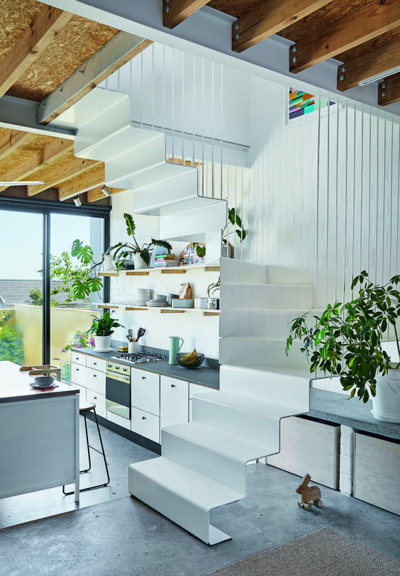 An under-stairs kitchen with open shelves and cabinets and potted plants is a stylish way to save a lot of space