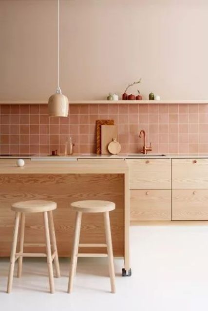 a beautiful modern kitchen with stained cabinets, a dusty pink square tile backsplash, a wooden kitchen island and wooden stools, hanging lamps