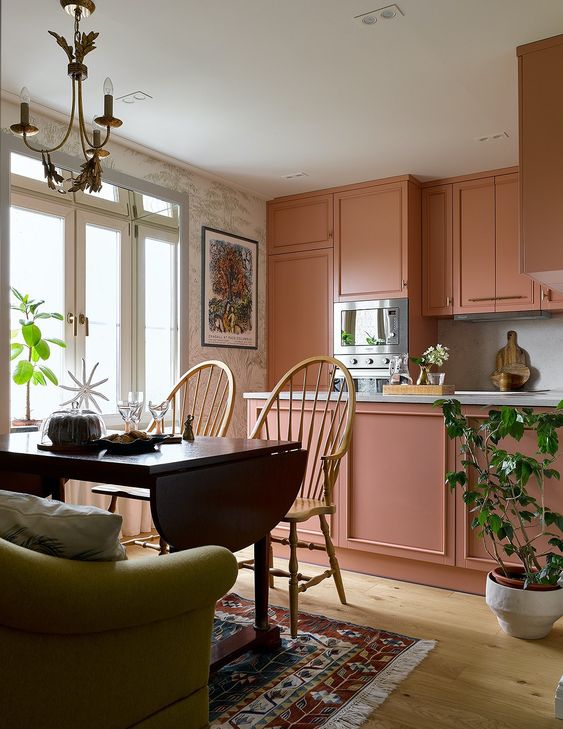 a beautiful peach pink kitchen with island and built-in appliances and a dining area with folding table