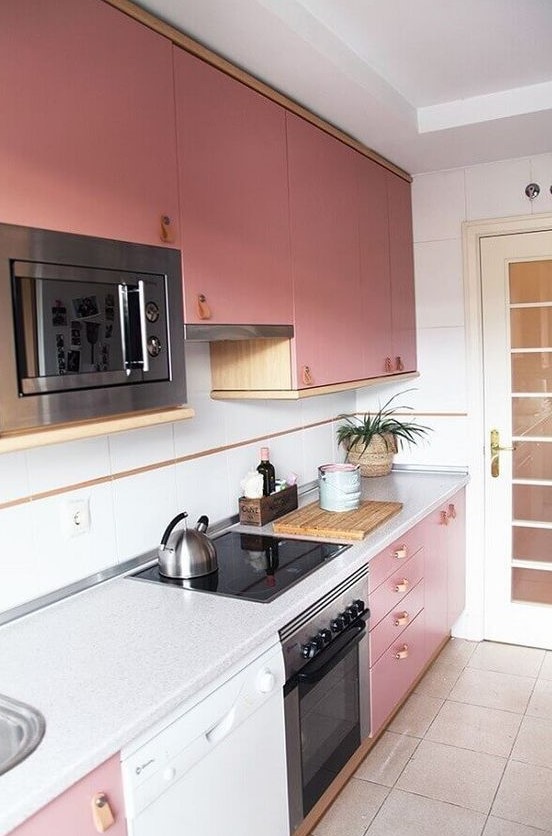A modern kitchen in bright pink with leather handles, neutral countertops and a splashback looks chic and cool