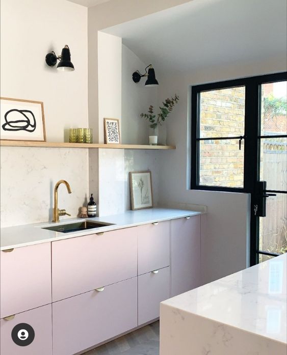 a modern kitchen with pale pink base cabinets, white stone worktops and splashback, long shelf and potted plants