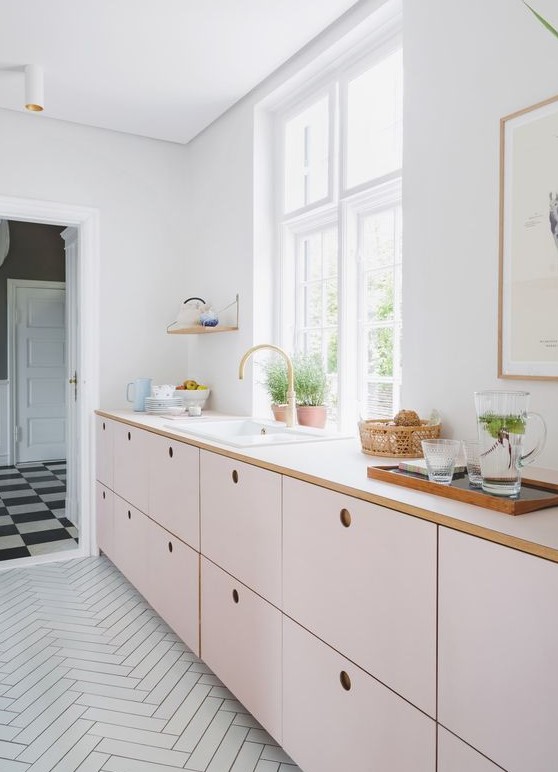 a delicately blushed kitchen with only base cabinets and white countertops, as well as lots of natural light