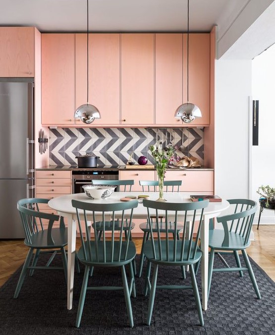 Here you'll find a light pink mid-century modern kitchen with a graphic tile backsplash and blue dining area