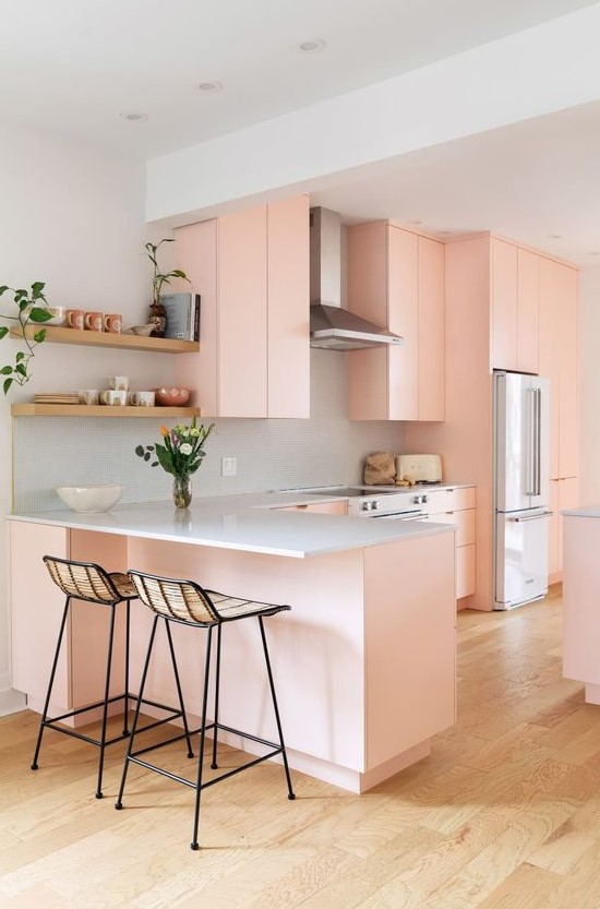 A beautiful peach pink flat-screen kitchen with white granite countertops, tall wicker stools and open shelving is fantastic