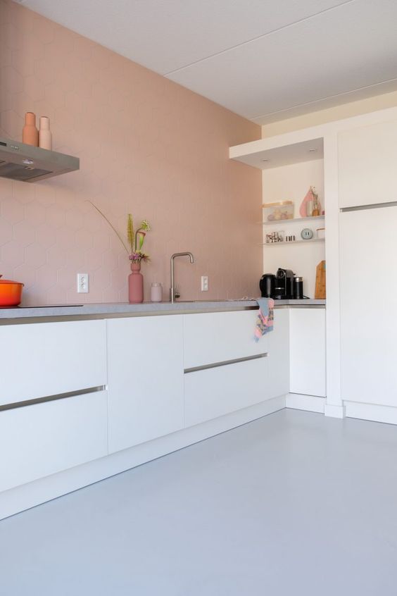 A minimalist kitchen in dusty pink with elegant white cabinets and gray stone countertops is a chic and beautiful space