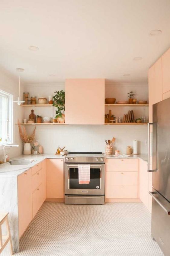 A peach pink kitchen with neutral stone countertops, open shelving, and pretty decor is a very cozy space