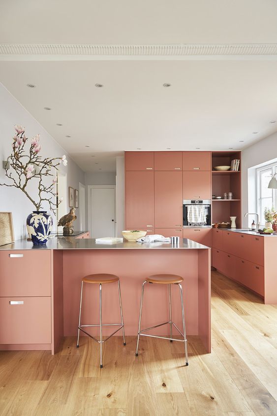 a salmon pink kitchen with elegant cabinets, a large kitchen island, stools and beautiful and elegant decor