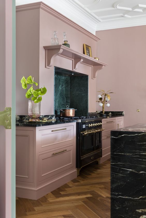 a sleek mauve kitchen with shaker cabinets, a black marble island, built-in appliances and gold accents