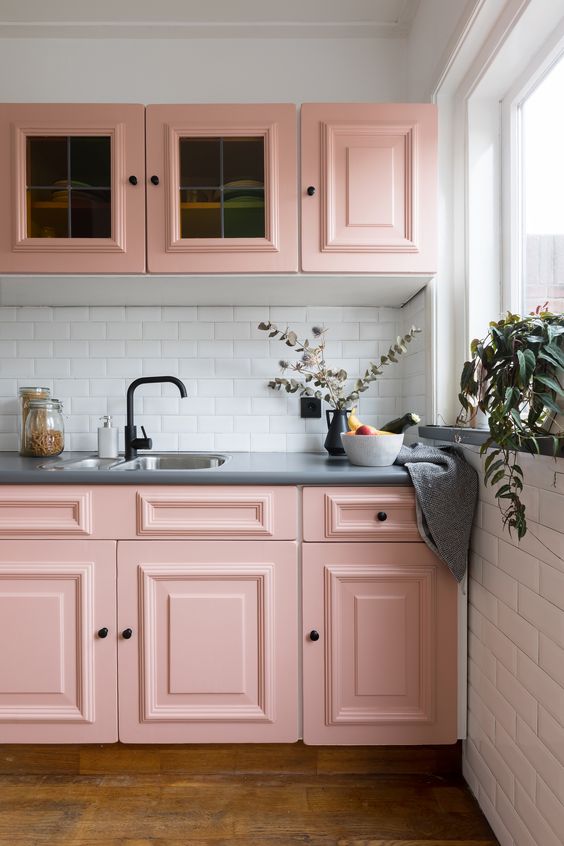 a stylish pink kitchen with shaker cabinets, a white subway tile backsplash, gray stone countertops, and black fixtures