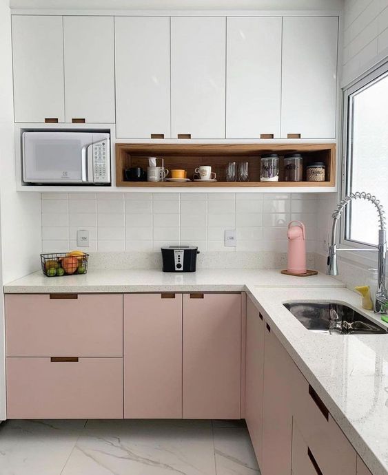 A two-tone kitchen with upper white and lower pink cabinets, a white tile backsplash, and white stone countertops is clean and chic