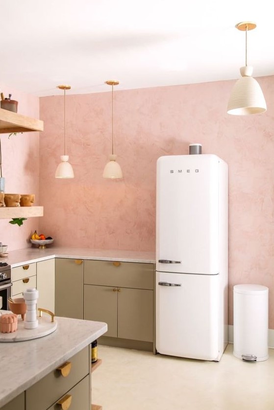 an inviting kitchen with pink walls, green cabinets, gold handles, pendant lamps and open shelves