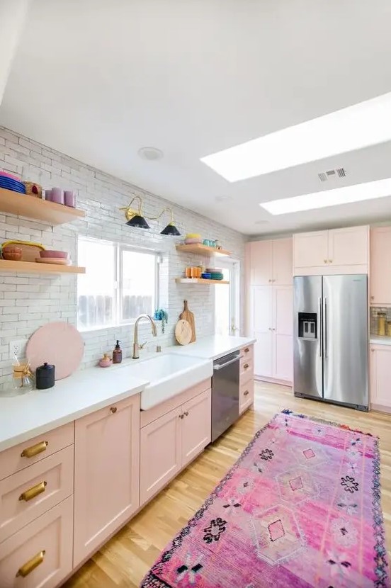 an eclectic kitchen with blush cabinets, a white tile backsplash, open shelving and colorful dinnerware