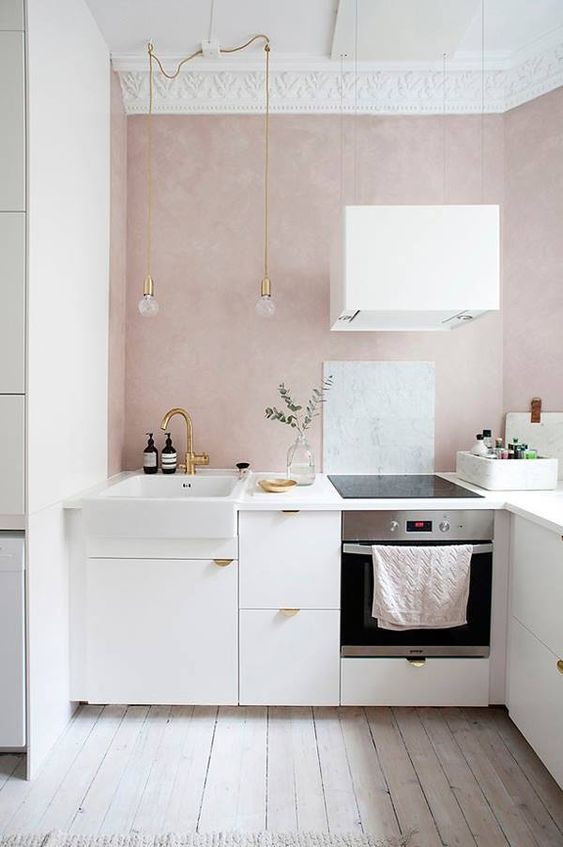 A glamorous, feminine kitchen with blush walls, gilded accents, and crown molding is a chic space you'll never want to leave