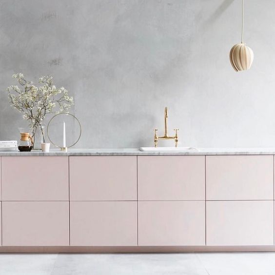 A calm, minimalist kitchen with gray plaster walls and blush cabinets is a heavenly beautiful space