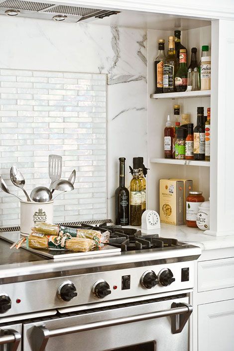 A modern white farmhouse kitchen with an alcove with shelves used to store oils and sauces needed for cooking