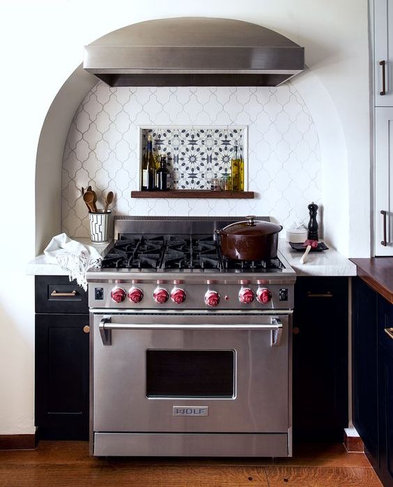 An arched niche with creative tiles and a stove, as well as two narrow cabinets on either side and an extractor hood, is a beautiful idea for a modern kitchen