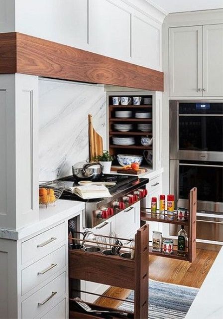 A white, modern farmhouse kitchen with built-in cupboards, a niche with a hidden extractor hood and porcelain niche shelves is a cool solution