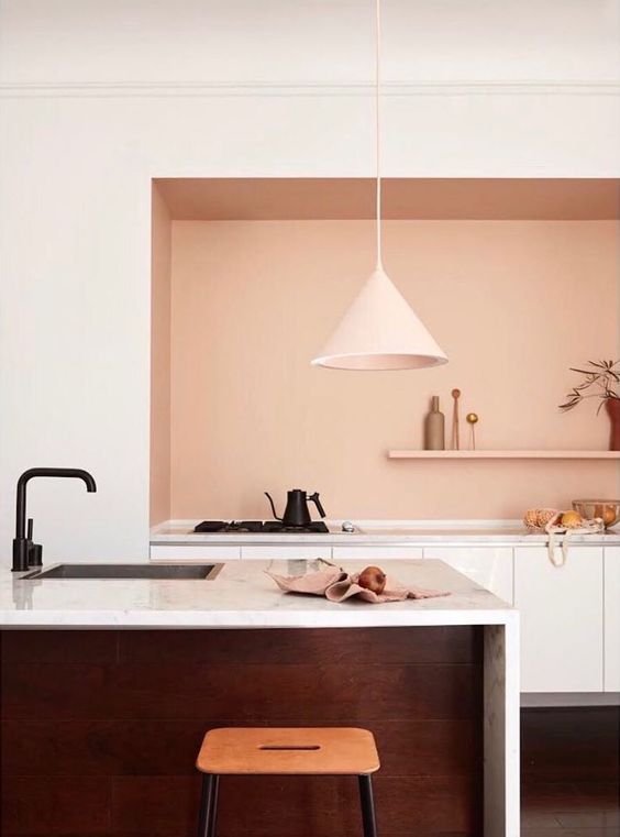 a modern kitchen with a large niche designed with peach color and housing a set of cabinets and an open shelf, which is a super unusual solution