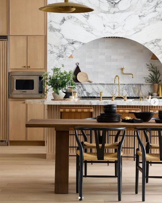 a sophisticated, modern farmhouse kitchen with elegant cabinetry and a fluted kitchen island, an arched alcove with a shelf for decoration and a dining area