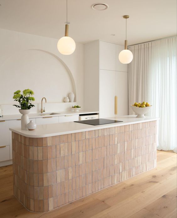 a sophisticated and beautiful kitchen with white cabinets, a kitchen island with terracotta tiles, an arched niche for decoration and pendant lamps