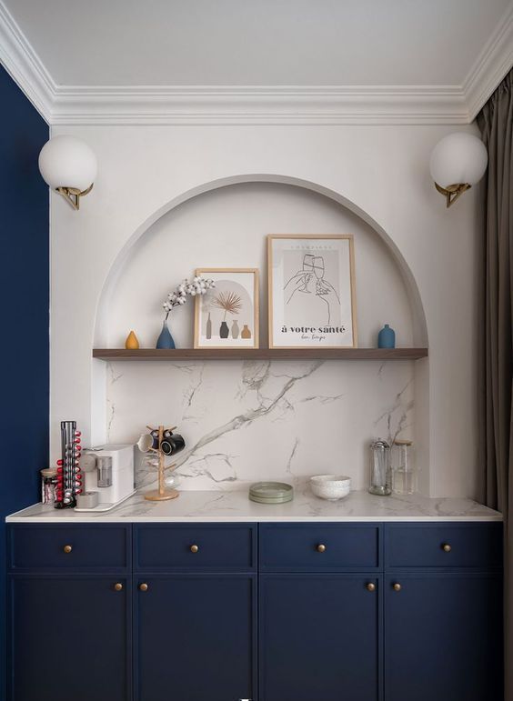 A sophisticated space with an arched alcove, navy blue cabinets, open shelving, some decor, and a coffee bar is a smart and elegant idea