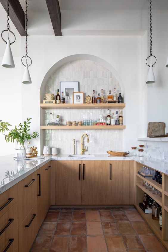 a stylish modern kitchen with stained base cabinets, white stone worktops and an arched alcove with open shelving used as a home bar