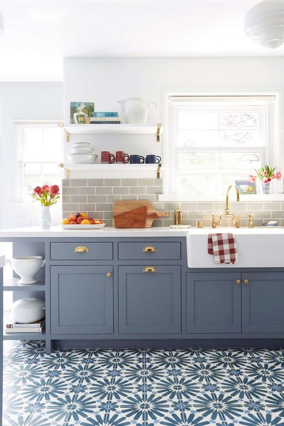a beautiful and cozy kitchen with blue shaker-style cabinets, a gray subway tile backsplash, a bold blue tile floor and open shelving