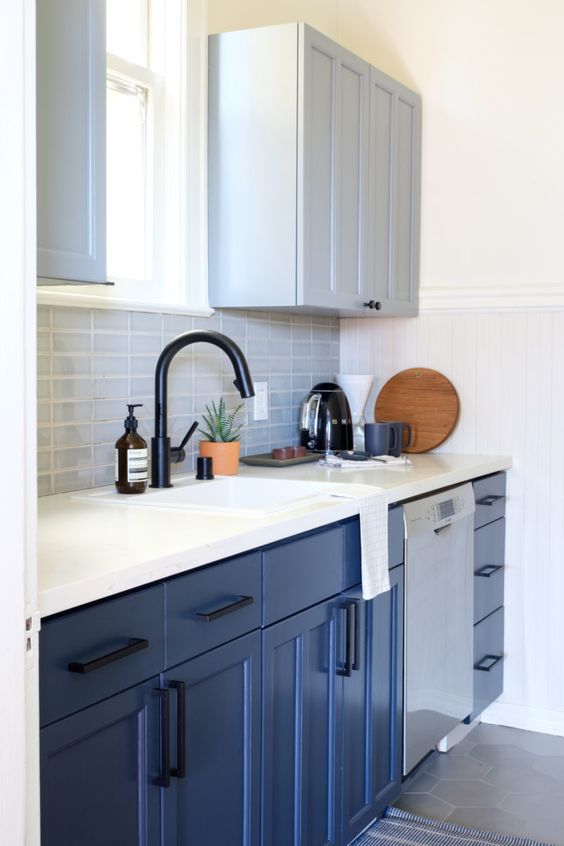 a stylish small kitchen with dove gray and bold blue cabinets, a gray tile backsplash and a white stone countertop