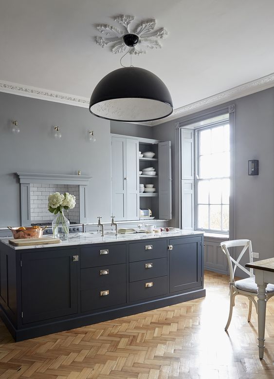 A chic dove gray kitchen with a midnight blue kitchen island and brass accents that make it more sophisticated and magnificent