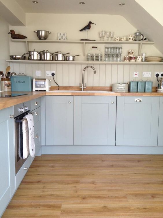 a light blue kitchen with a dove gray wall and beadboard backsplash and wooden countertops that warm and soften the look
