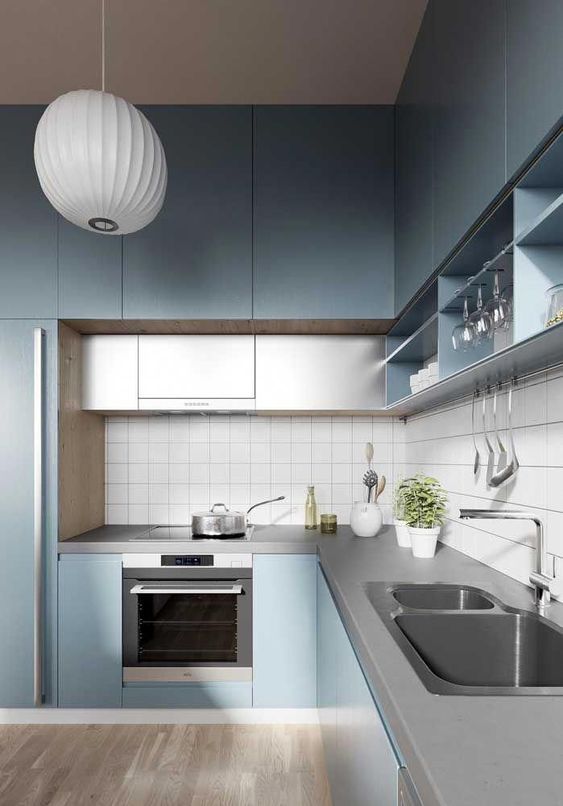 a minimalist light blue kitchen with gray additional cabinets and a concrete worktop and a back wall made of white tiles
