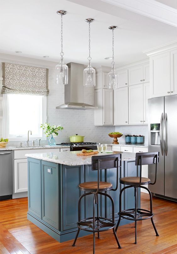A white kitchen with a gray tile backsplash and a blue kitchen island and white stone countertops is chic