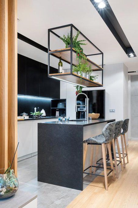 a modern black and white kitchen with built-in lighting, a kitchen island with a waterfall countertop and a hanging shelf