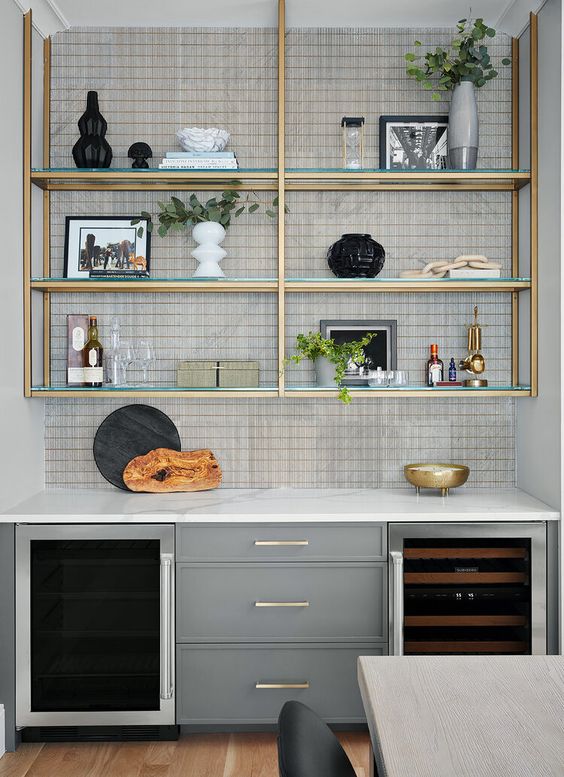 A modern kitchen with gray cabinets and a glass shelf with gold accents is a chic and cool idea