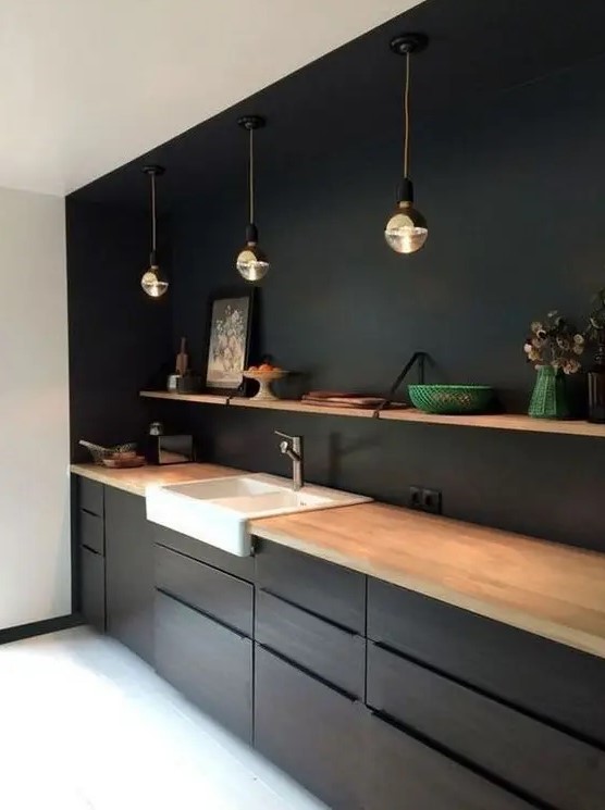 A minimalist black kitchen jazzed up with a white sink and wooden shelf and countertops for a fresh look