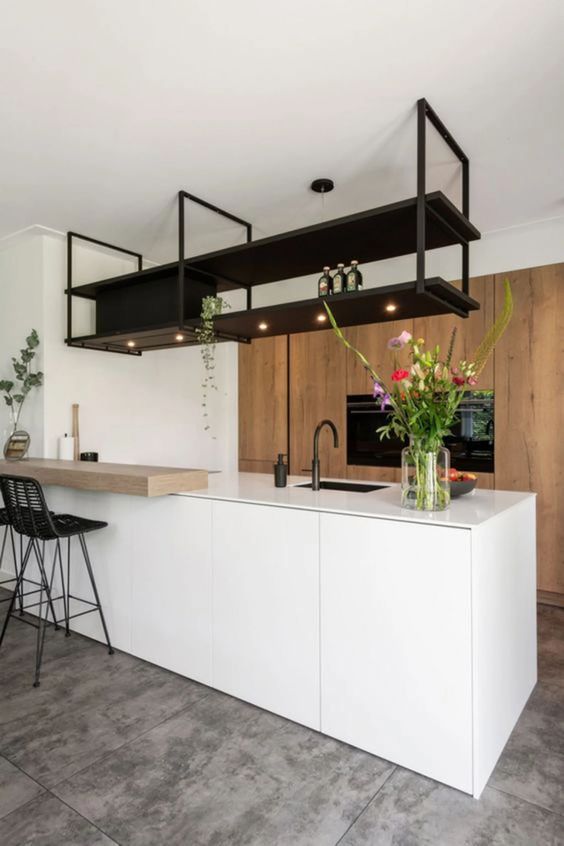 a minimalist kitchen with large stained storage, a sleek white kitchen island, black hanging shelf and black stools