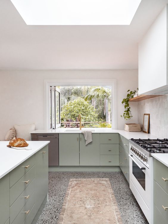 a sage green kitchen with flat-panel cabinets, a white range hood, open shelving and a window in place of a backsplash