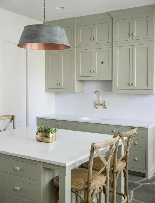 a small sage green kitchen with shaker and flat-panel cabinets, a white subway tile backsplash and white countertops, and a statement brushed lamp