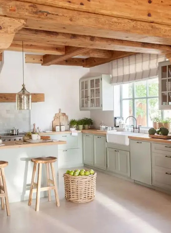 a modern farmhouse kitchen with wooden beams on the ceiling, bright green shaker-style cabinets, butcher block countertops, a basket for storage and a pendant lamp