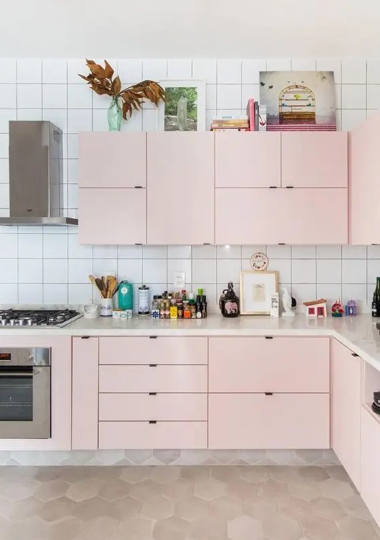 A modern kitchen in light pink with a white tiled back wall and built-in appliances is particularly chic