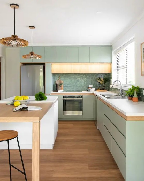 A modern, pastel green kitchen with sleek cabinets, white stone countertops, a glossy green tile backsplash, and woven pendant lamps