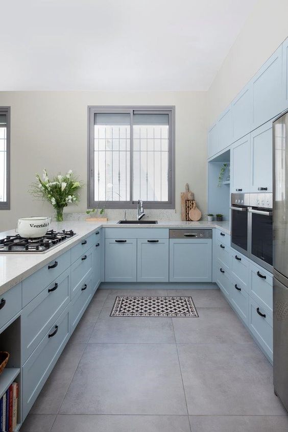 A pastel blue kitchen with shaker cabinets, white granite countertops, and black faucets and handles is amazing