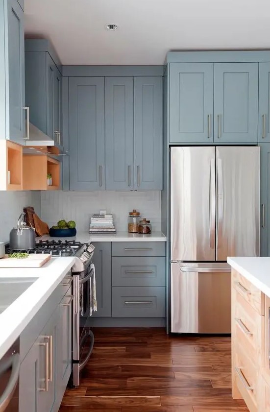 A pastel blue Shaker-style kitchen with a white square tile backsplash, white countertops and stainless steel handles is super chic and airy