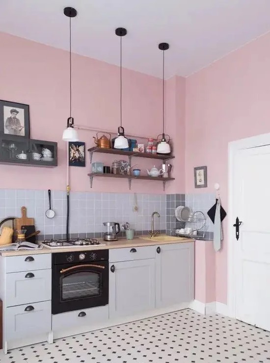 a pink kitchen with gray base cabinets, butcher block countertops, a gray tile backsplash, pendant lamps and a printed tile floor