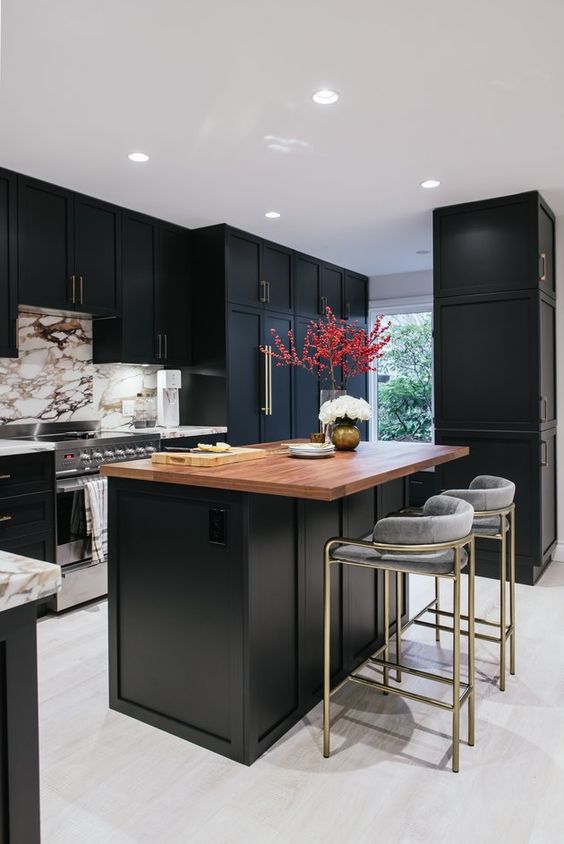 a sophisticated black kitchen with a white marble backsplash, a black kitchen island with a butcher block countertop and gray stools