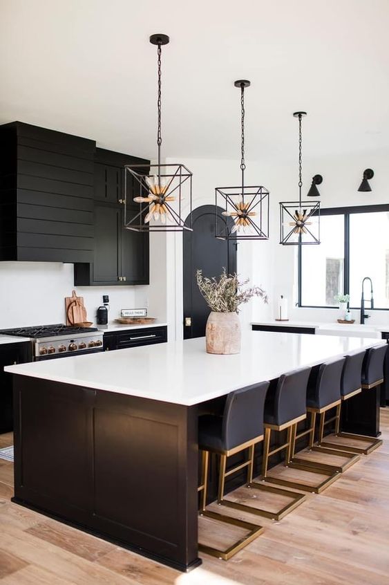 a black farmhouse kitchen with shaker cabinets, a beaded range hood, a large kitchen island with lots of stools