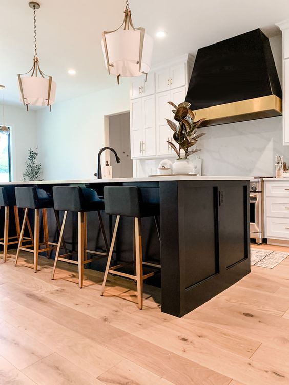 A creative black and white kitchen with shaker cabinets, a large kitchen island, a striking black range hood and stools
