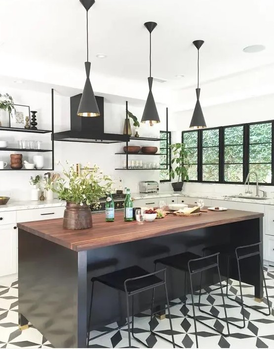 A white farmhouse kitchen accented with a black mosaic floor, black kitchen island and black pendant lamps